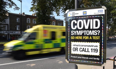 An ambulance drives past a sign displaying a Covid helpline in London.