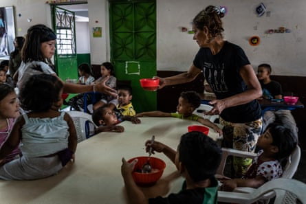 Community volunteers help serve food to children at a kitchen run by Alimenta la Solidaridad, a local NGO working in Petare, in February 2019