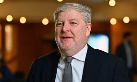 Angus Roberston smiling, with out-of-focus lights in the background