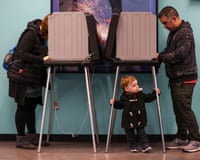 people vote at voting booths, with a child under one of them