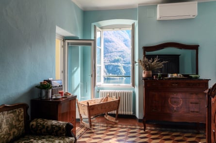 A hotel room with antique furniture, a wooden crib and a view of a lake.