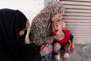 A woman in a chador hugs a distraught child