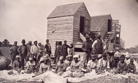 old black and white photo of people gathered around some wooden sheds