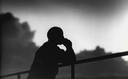 A man looking over a railing in shadow