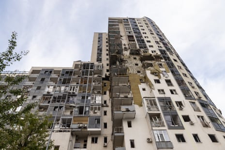 A multi-story residential building stands heavily damaged in Kharkiv.