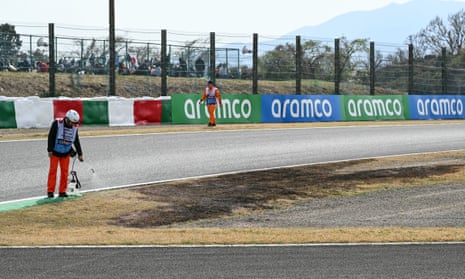 Track marshals water down the dried out grass next to a burnt patch at Suzuka Circuit