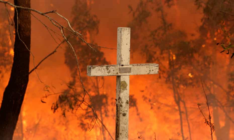 A bushfire burns behind a cross at Possum Brush, near Taree.