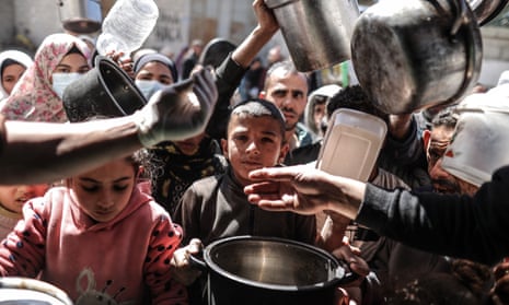 Palestinian people queue for food distributed by a charity in Deir al Balah, central Gaza