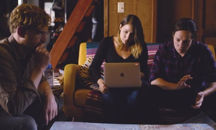 Three younger adults sit on a couch in front of a computer.