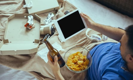 Man with empty pizza box, bowl of crisps, beer bottle, chocolate wrapper