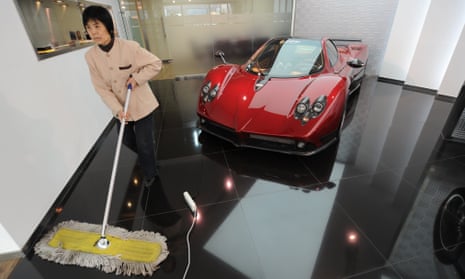 A cleaner sweeps the floor next to a Pagani sportscar in a luxury car showroom in Beijing.
