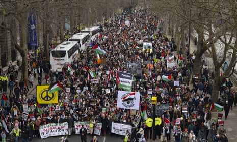 An aerial view of thousands of people, holding banners and Palestinian flags, on a London street