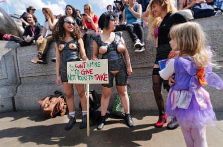 Women with their breasts out, holding placards, on a Slutwalk in protest against sexual violence, in London, June 2011