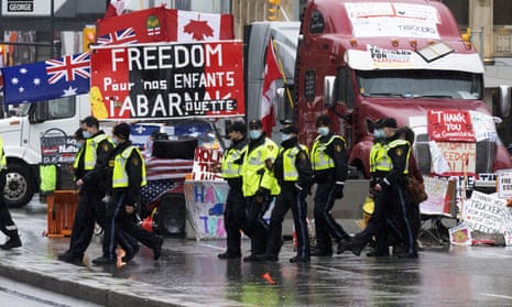 Ontario provincial police officers walk in front of the trucker blockade protest in Ottawa on Thursday.