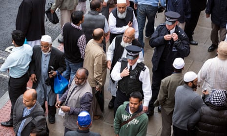 Policemen pass through Muslims leaving the East London Mosque after Friday prayers.