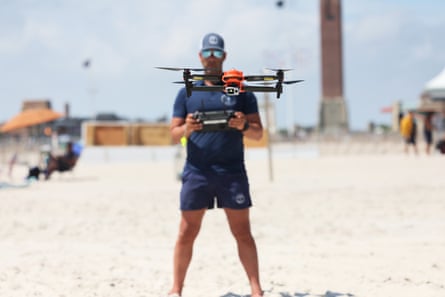 a lifeguard flies a drone on a beach