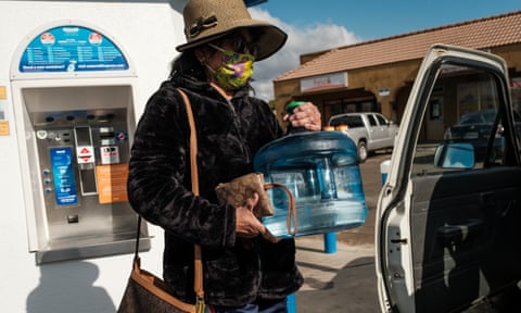 A woman fills up drinking water containers from a kiosk in Orosi.