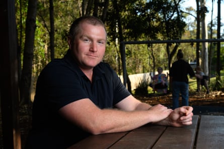 Alex Hogan sits at a table with a swing set in the background