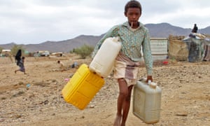 A displaced child carries water at a camp in Yemen
