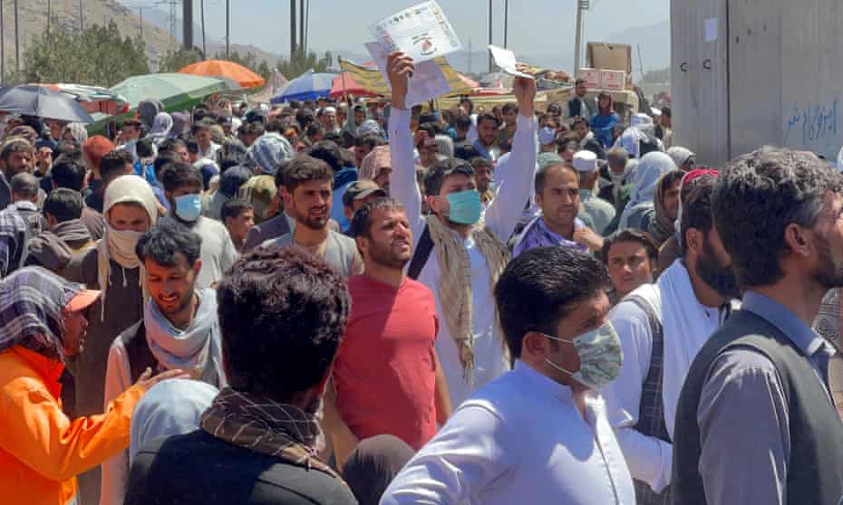 Crowds of people try to show their documents to US troops outside the Kabul airport.