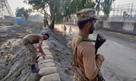 Members of Pakistan's army guard a dike to protect a power station.