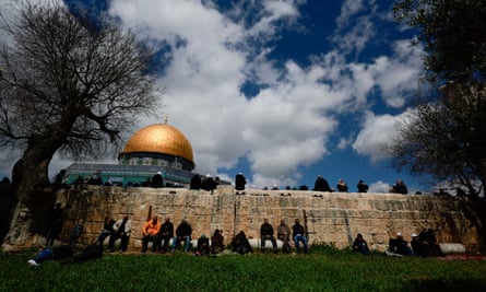 Group of men in front of light-coloured stone wall, with the mosque’s gold dome in the background