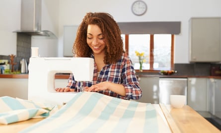 Woman at kitchen table using sewing machine.
A woman makes curtains at home using a sewing machine.