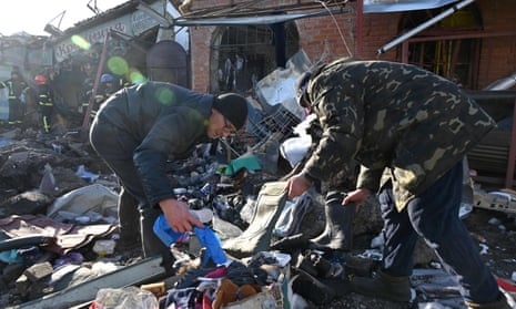 Sellers collect some goods from destroyed shops on a local market after a Russian missile strike in Shevchenkove village.