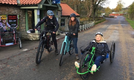Two adults on e-bikes and one on a hand bike