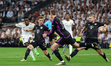 Vinicius Junior of Real Madrid shoots whilst under pressure from Joshua Kimmich and Matthijs de Ligt of Bayern Munich.