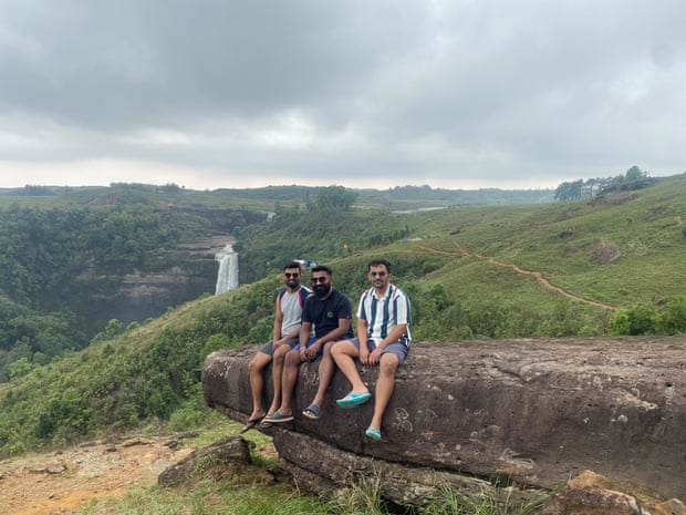 Friends Rishab Baid, Kaushal Jain and Nabendu Goswami sit on a rocky ledge near Phe Phe falls, Meghalaya state