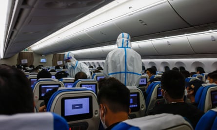 Le personnel de la compagnie aérienne portant des combinaisons de protection vérifie les passagers à leur arrivée à l'aéroport international de Xiamen Gaoqi, en Chine, le 20 décembre 2022.