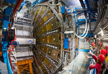 People with red hard hats next to Large Hadron Collider