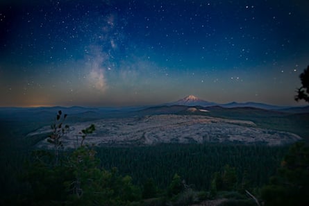 Night sky view from Mount Hoffman toward Mount Shasta with Little Glass Mountain Obsidian Flow in the middle ground.