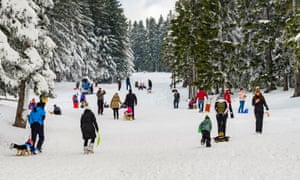 Enfants avec parents faisant de la luge et s'amusant sur la première neige