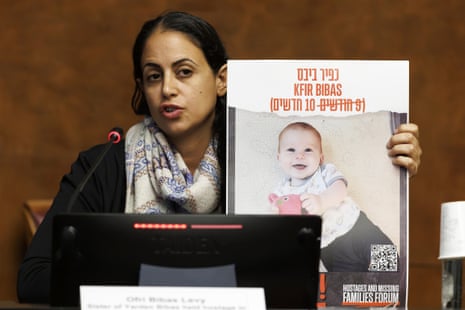 Ofri Bibas Levy, sister of Yarden Bibas, holds up a picture of Kfir during a press conference in Geneva on 14 November.