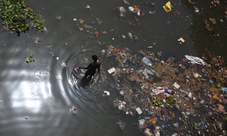 A scavenger looks for recyclable items on the banks of the Yamuna river.