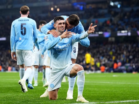 Phil Foden kneels celebrating a goal as Ruben Dias hugs him from behind