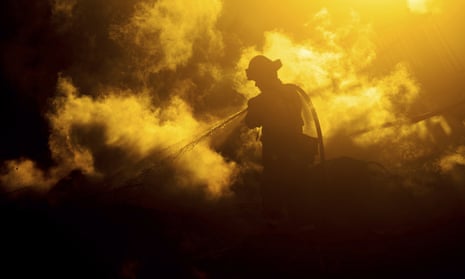 A firefighter sprays water on a leveled home as the Hillside fire burns in San Bernardino, on 31 October 2019. Whipped by strong wind, the blaze destroyed multiple residences.