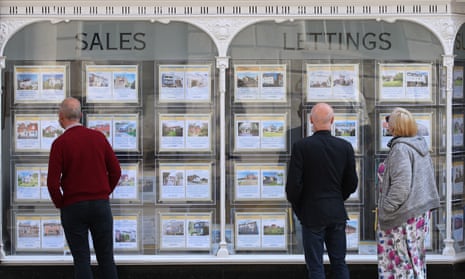 People looking at sales and letting notices displayed in the window of an estate agent