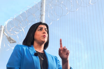 Mahmood speaking in front of a fence topped with barbed wire