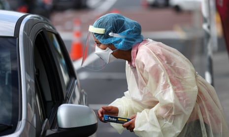 A health worker hands out rapid antigen tests to a waiting queue of cars in Auckland, New Zealand
