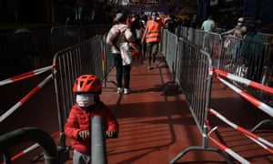 A kid wearing a protective face mask stands with his scooter in a line at a free food distribution for people in need on May 9, 2020 in Geneva