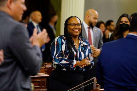 A woman who is smiling is surrounded by people applauding her