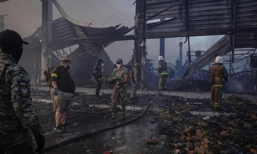 Rescuers and service members work at a site of a shopping mall hit by a Russian missile strike.