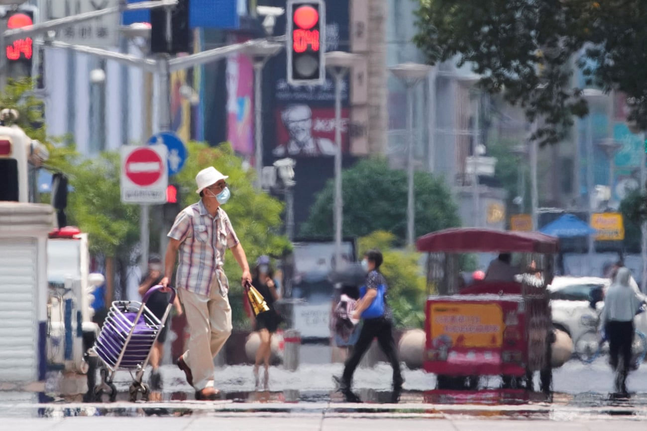 A man wearing a face mask pulls a cart on a street amid a heatwave warning in Shanghai, 13 July