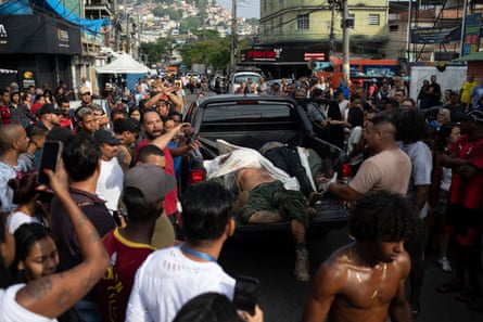 A crowd around a pickup truck with bodies of dead people