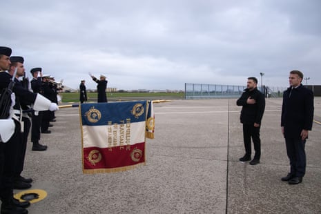French President Emmanuel Macron, right, and Ukrainian President Volodymyr Zelenskyy listen to national anthem at the Villacoublay air base near Paris.
