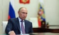 Vladimir Putin sits at a desk looking serious.