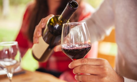 Person pouring red wine into a glass